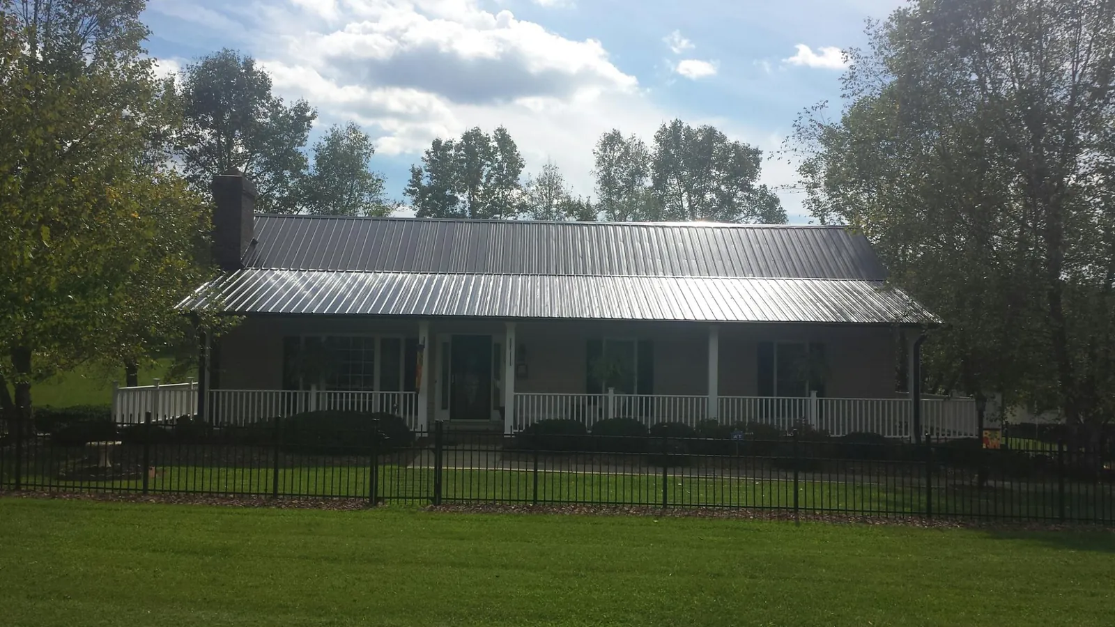 Gray metal roof on a brick ranch with a full width front porch — Gutter Guard Installation work by our crew in Williamsville