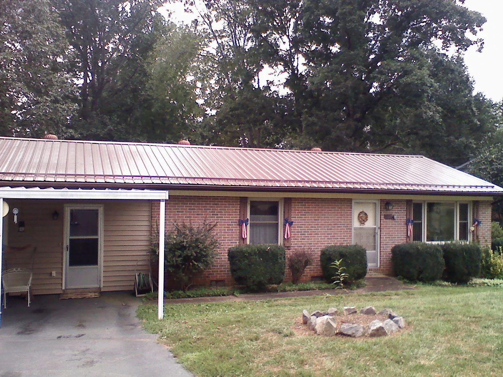 Bronze metal roof and carport on a brick ranch home — Roof Repair work by our crew in Williamsville