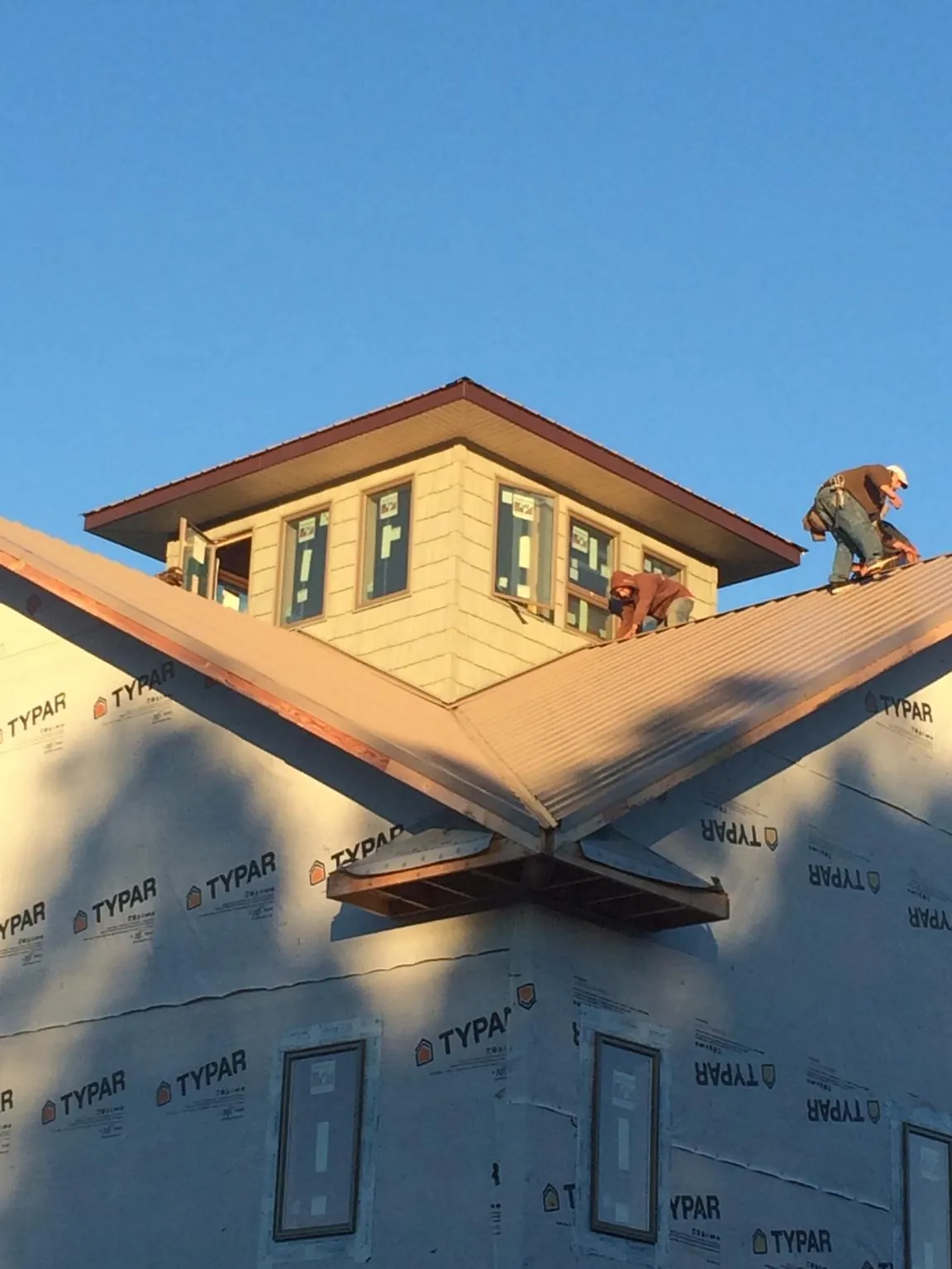 Roofers working around a rooftop cupola on a new metal roof at sunset — Roof Waterproofing in Williamsville by Roofing Brothers